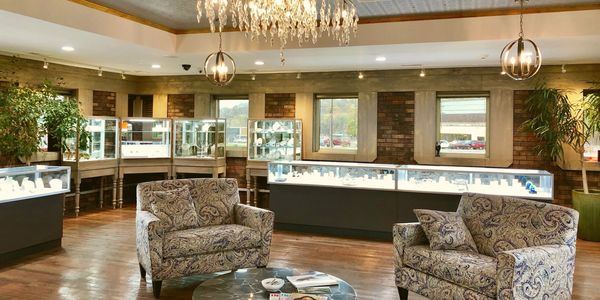 Two loveseats with jewelry cases lining the exterior with chandelier hanging from ceiling