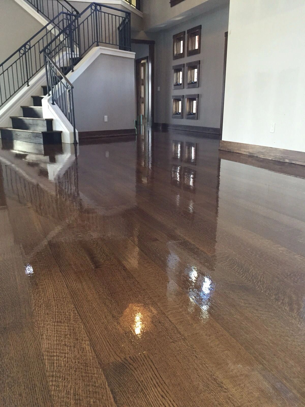 Shiny polished wooden floor with staircase and wall decor.