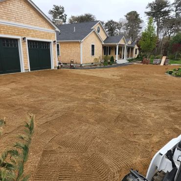 Freshly leveled dirt driveway in front of a suburban house.