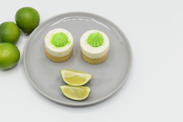 A birds eye view of 2 Lime Tarts and 2 lime slices laid out in the form of a smiley face