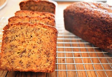 Close-up shot of multiple slices of banana bread next to a loaf