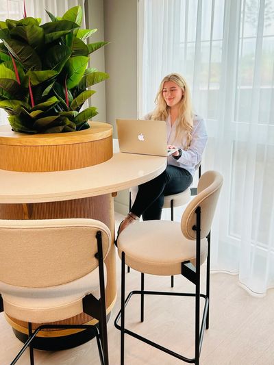 Therapist sat at a table with their laptop open smiling