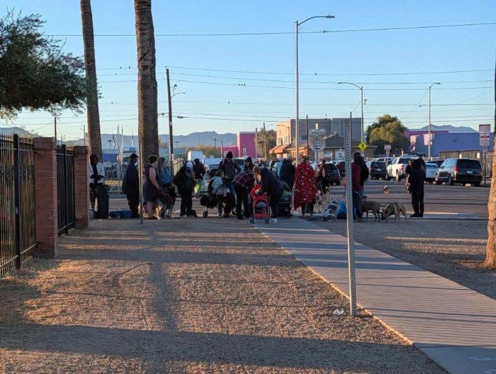 Group of people gathered on a sidewalk in an urban area during daylight.