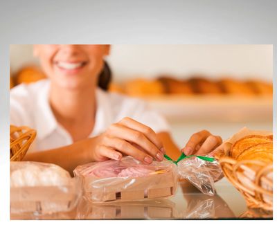 A lady wrapping food in a container to sell with a green ribbon