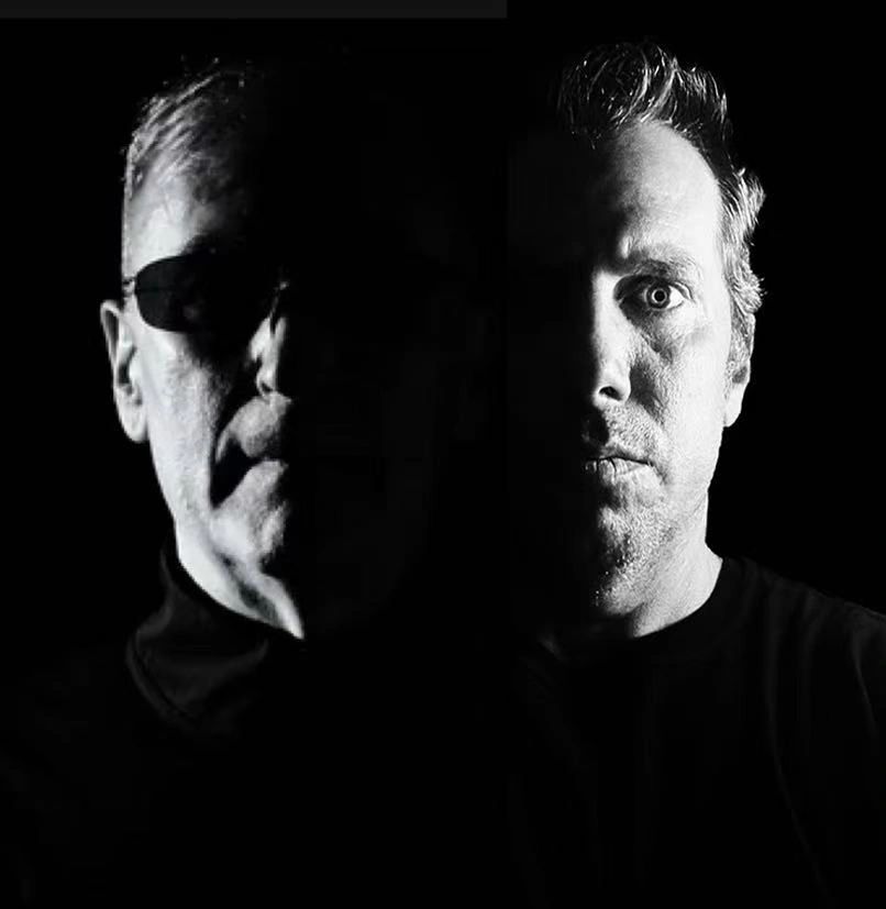 Two men face forward, half of each face illuminated against a black background.