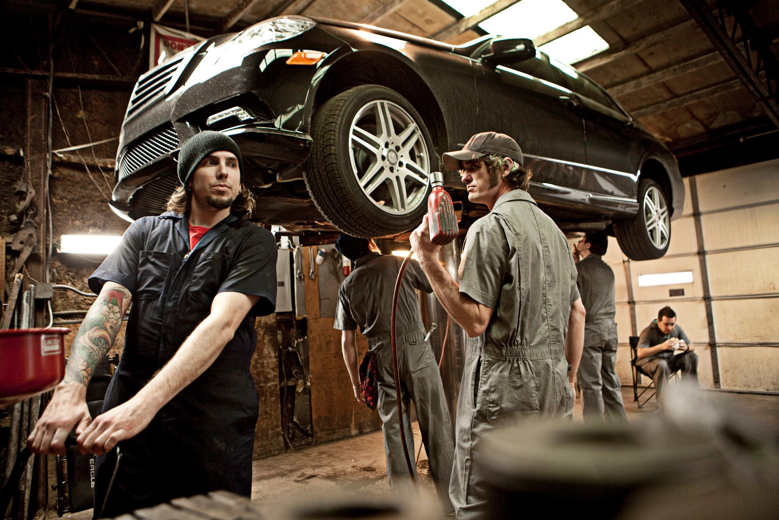 Mechanics working on a car lifted in a garage.