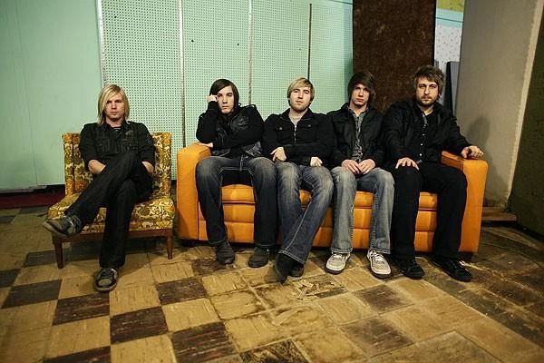 Five young men sitting on two couches in a worn room.