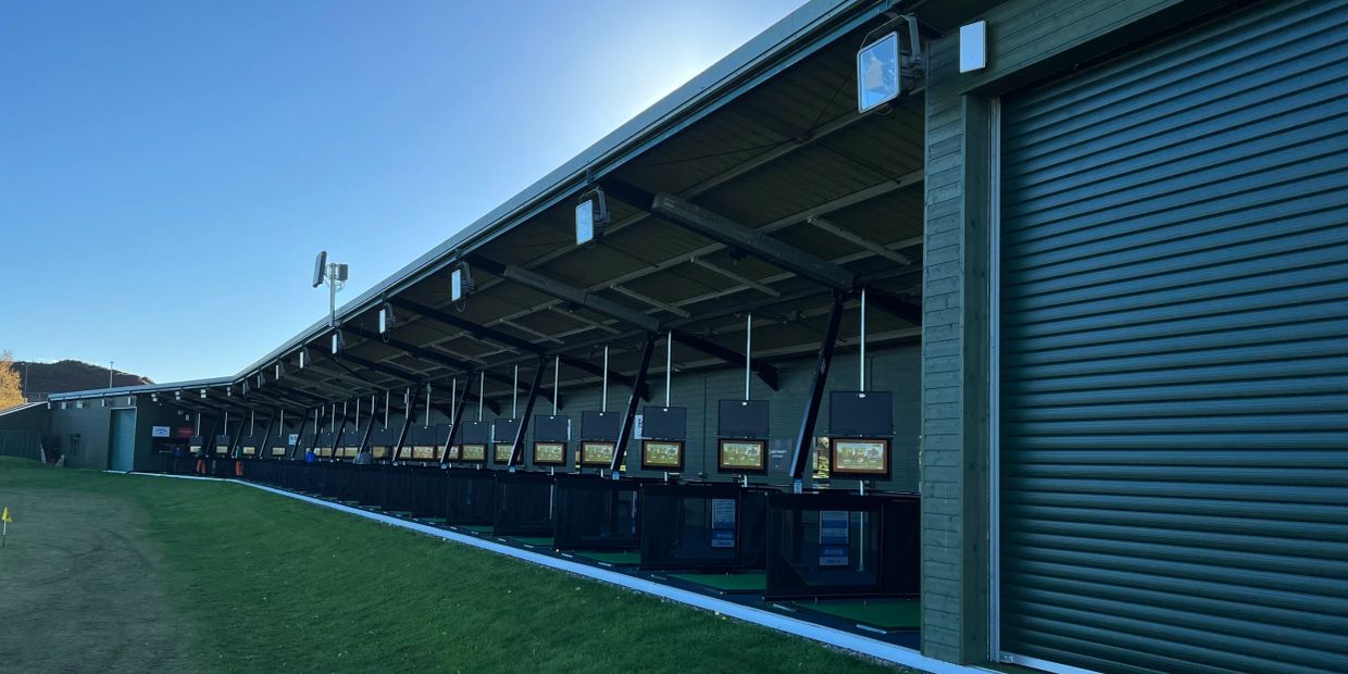 Modern golf driving range stalls with digital screens.