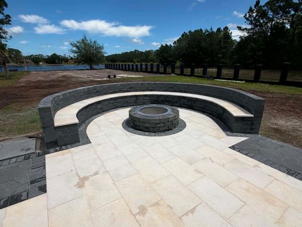 Curved stone bench surrounding a circular fire pit outdoors.