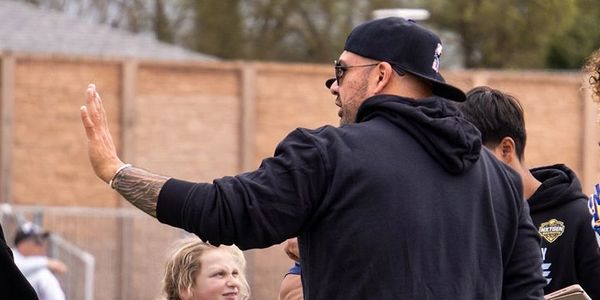 Coach giving high fives to young athletes during a sports event.