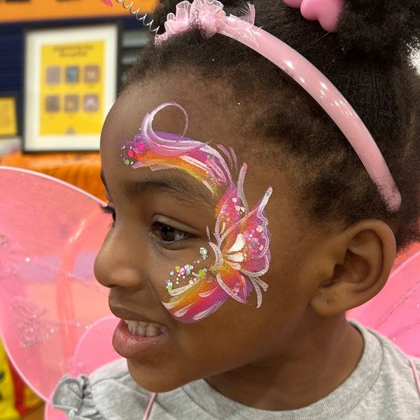 Little girl with butterfly face paint and fairy wings.