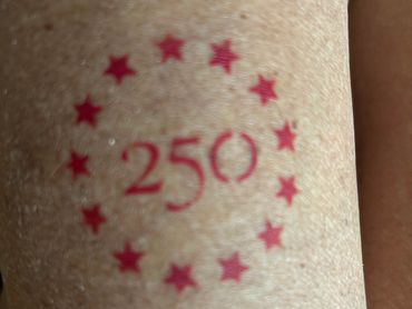 Red tattoo with number 250 and stars around it.