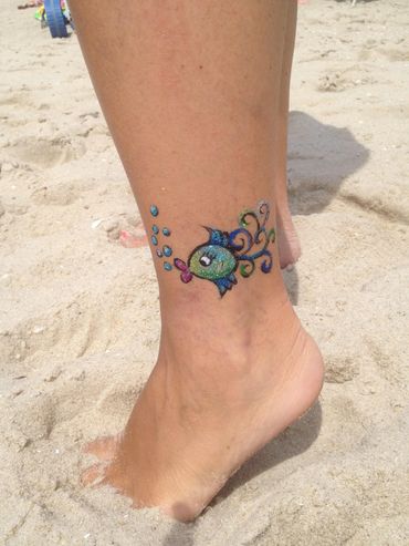 Colorful fish tattoo on ankle with bubbles.
