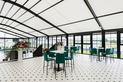 Elegant indoor seating area with green chairs and floral decorations.