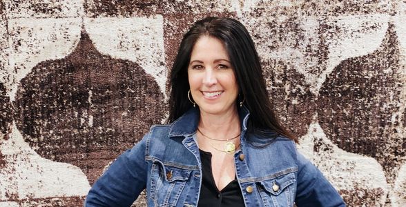 Luxury realtor Gena Roberson poses in front of outdoor wall mural in Mckinney, Texas 