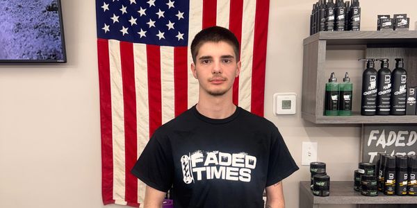 Young man wearing a Faded Times t-shirt standing in front of an American flag.