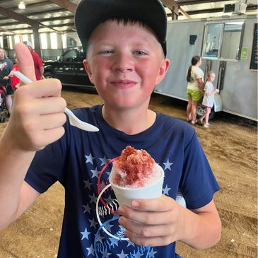 Boy enjoying a snow cone at an indoor event.