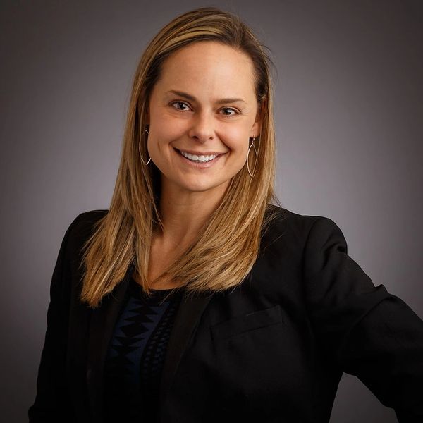 Smiling woman with straight blonde hair and black blazer.
