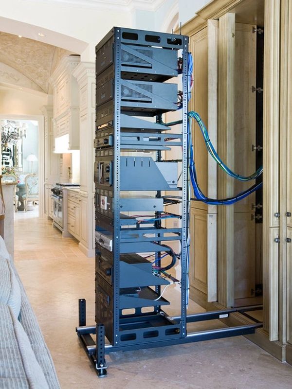 Tall server rack with cables next to kitchen area.