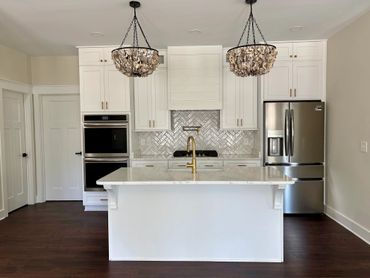 Modern kitchen with white cabinetry, marble island, and stainless steel appliances.
