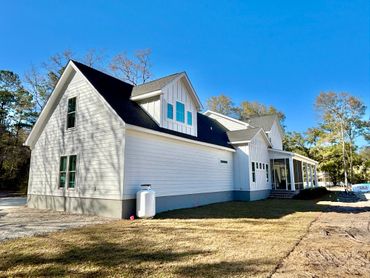 A modern white house with a dark roof under a clear blue sky.