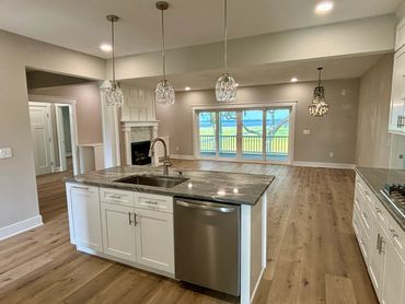 Modern kitchen with island, stainless steel appliances, and large window.