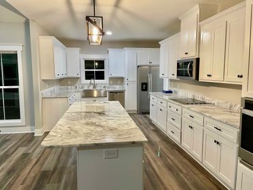 Modern kitchen with white cabinets and marble countertops.