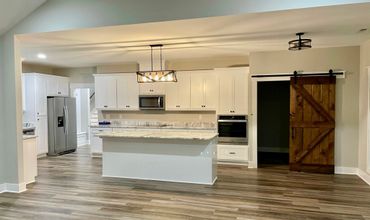 Modern kitchen with white cabinets and a wooden barn door.
