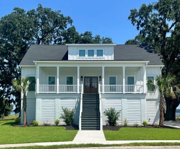 A modern white house with a front porch and stairs leading up to the entrance.