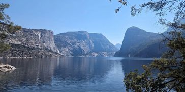 Hetch Hetchy reservoir on a warm summer day with granite walls framing the banks.