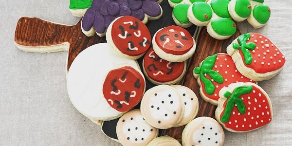 Colorful fruit-themed sugar cookies arranged on a wooden board.
