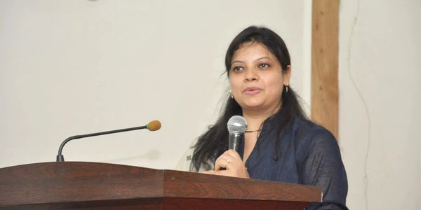 A woman speaking confidently at a podium with a microphone.