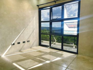 Sunlit empty room with large windows and outdoor view.