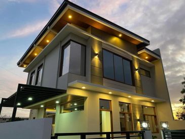 Modern two-story house during sunset with exterior lights on.
