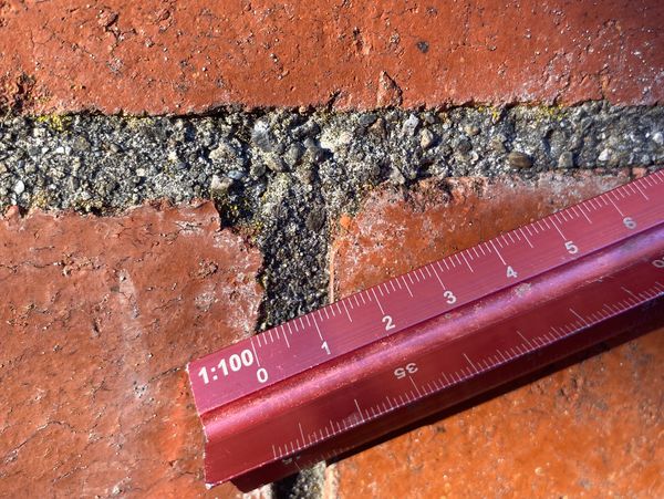 Red ruler on a brick wall gap