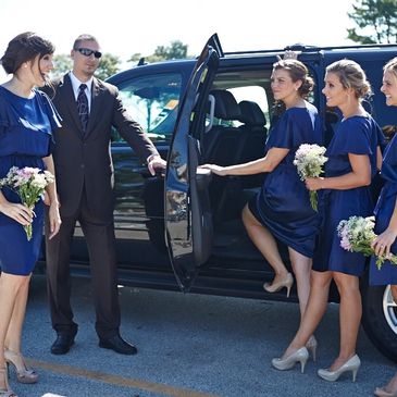 Some girls sitting inside a black color big car