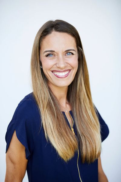 Smiling woman with long blonde hair wearing a navy blue top.