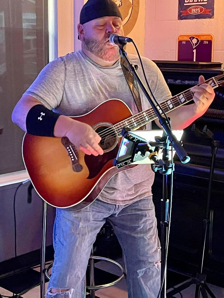 Man passionately singing and playing guitar on stage.