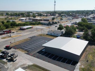 A large metal building with a newly paved parking lot in a small town.