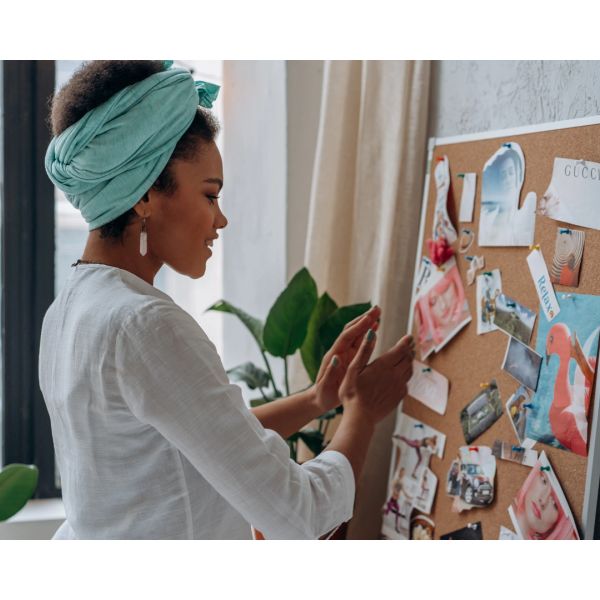 Woman organizing a pinboard with pictures and notes.