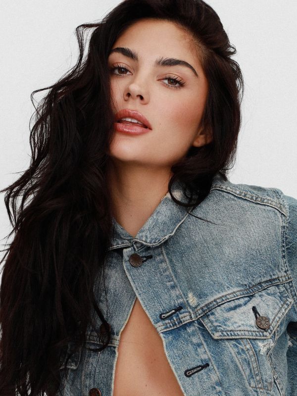 Woman with long dark hair wearing a denim jacket.