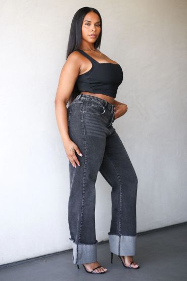 Woman posing in black top and rolled-up jeans.