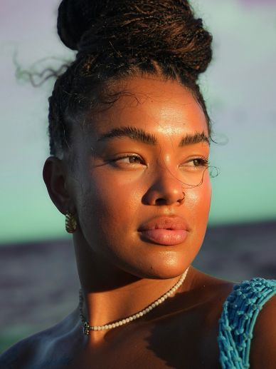 Young woman with braided hair enjoying golden hour light near water.