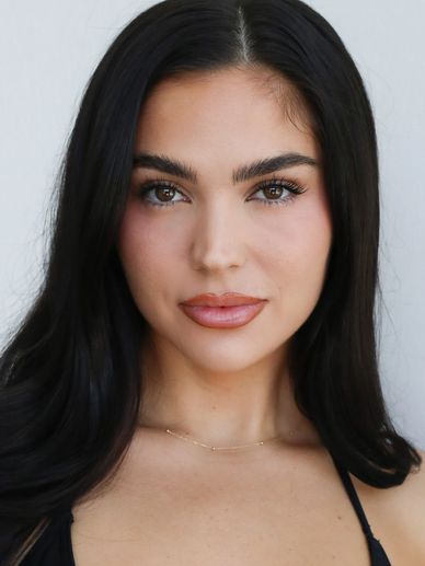 Close-up portrait of a woman with long dark hair and natural makeup.