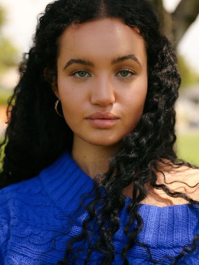 Portrait of a woman with curly hair in a blue sweater.