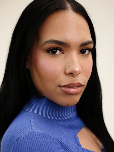 Close-up portrait of a woman with long black hair and a blue top.
