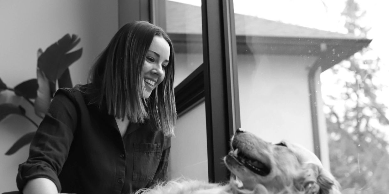 Woman smiling at a happy dog indoors.