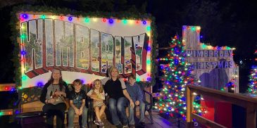 Family posing by holiday lights at Timberly Christmas.