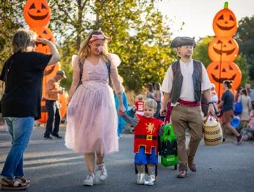 Family dressed in Halloween costumes walking outdoors.