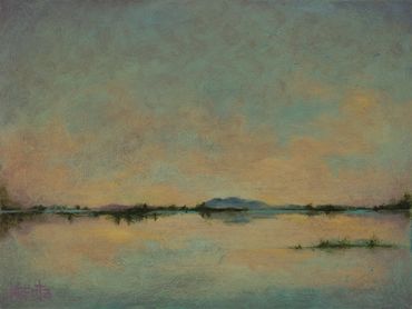 Tranquil landscape with water and distant hills at sunset.